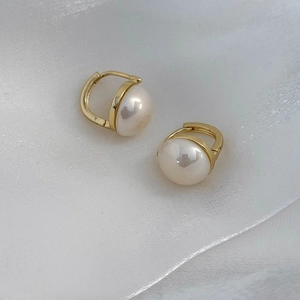 Dettaglio degli orecchini a cerchio con perle champagne su elegante seta bianca