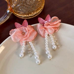 Detailed close-up of mesh flower earrings with pink acrylic butterfly and pearl tassels