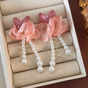 Detailed macro view of pink chiffon flower earrings with elegant white pearl tassels