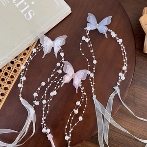 Detailed close-up of butterfly pearl hair accessories on a natural wood and wicker tray