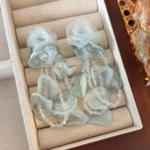 Detailed macro view of light green organza floral earrings with crystal beads in a soft box
