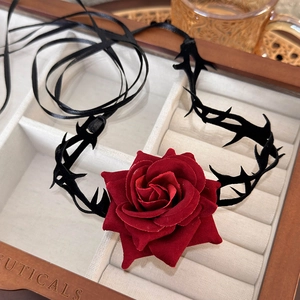 Detail of dark red velvet rose choker with black thorn elements and satin ribbon ties