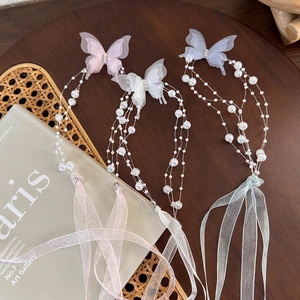 Detailed view of layered butterfly hair clips with pearls and organza ribbons in three colors