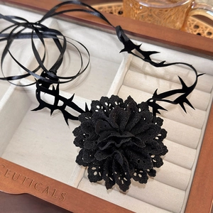 Detail of a handmade black lace flower choker with dark thorn ribbons in a vintage wooden box