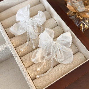 Detail of white organza bow hair clip with translucent beads and pearls in a jewelry box