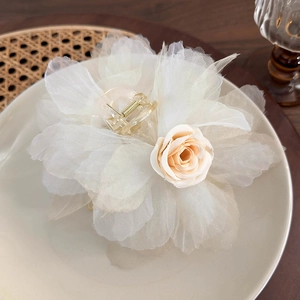 Dettaglio della pinza per capelli con fiore in rete crema e rosa rosa su piatto di ceramica