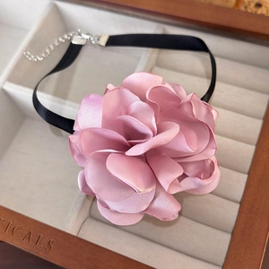 Detailed view of handmade pink silk flower choker with soft petals and black satin strap