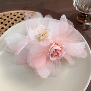 Dettaglio ravvicinato dei petali in organza rosa e bianchi su una pinza per capelli a fiore