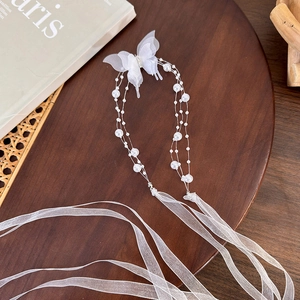 Detailed macro view of white mesh butterfly hair ribbon with elegant pearls on a wooden tray