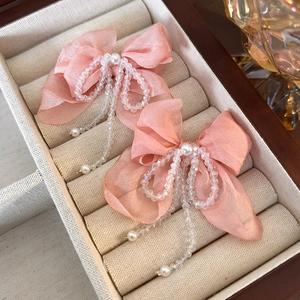 Detail of pink organza bow hair clip with pearl center and crystal bead tassels
