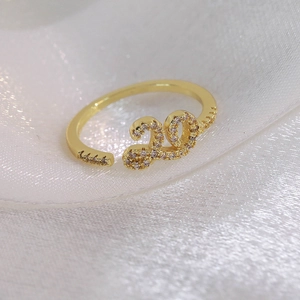 Détail d'une bague dorée 18 carats avec le chiffre 20 serti de zircons brillants