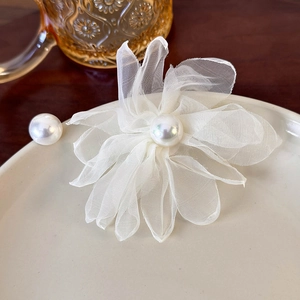 Close-up of elegant mesh flower earring with a central pearl on a ceramic plate