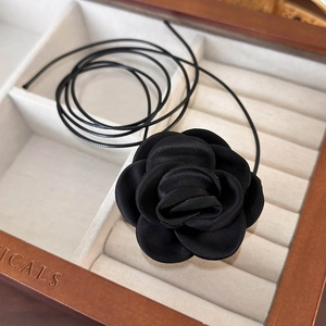 Macro detail of a 3D black satin handmade rose choker necklace in a wooden gift box