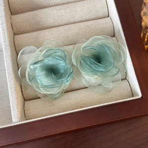 Detailed macro view of light green organza rose earrings with layered petals on display