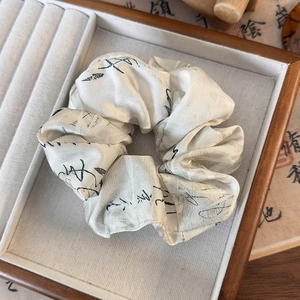 Détail de chouchou en satin avec calligraphie chinoise sur plateau en bois