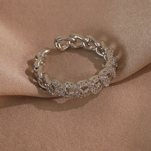 Gros plan d'une bague chaîne gourmette argentée avec zircons sur satin champagne