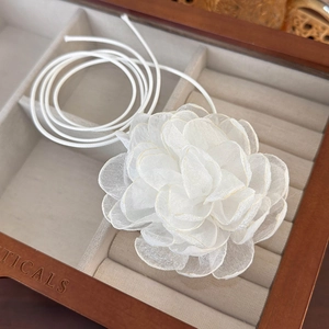 Detailed macro view of handmade white fabric flower choker with golden edge stitching