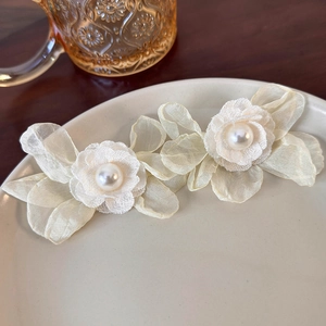 Close-up of yellow mesh flower earrings featuring layers of organza and pearl centers
