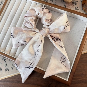Détail du chouchou nœud en soie avec motif de calligraphie noire en beige doux