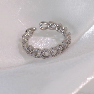 Détail macro d'une bague chaîne cubaine argentée sertie de zircons sur soie blanche