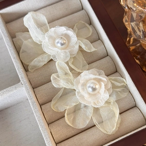 Detail view of lace flower hair clips with large central pearls on a warm wooden background