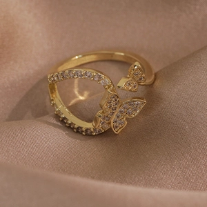 Vue détaillée d'une bague papillon dorée avec zircons micro-pavés sur un tissu de soie champagne
