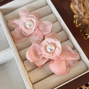Detail of pink mesh flower earrings with central faux pearl on beige velvet tray