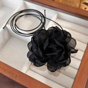 Macro detail of a 3D black tulle rose choker on a velvet jewelry display box