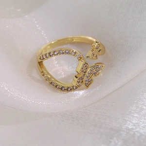 Détail de la bague papillon dorée avec zircons blancs sur fond de soie