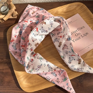 Pink silk headband with cute cartoon dog patterns on a wooden tray with candle