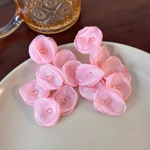 Macro shot of pink organza handmade flower earrings on a ceramic plate with warm light