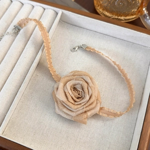 Macro detail of a champagne satin rose choker necklace with lace ribbon in a velvet jewelry box