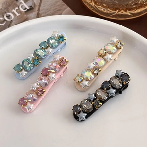 Detailed macro view of four glittery duckbill hair clips with rhinestones and stars