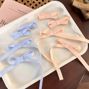 Detailed view of ballet-style ribbon bow hair clips in pastel blue and pink on a tray