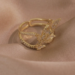 Détail d'une bague papillon dorée avec zircons micro-sertis sur soie de luxe champagne
