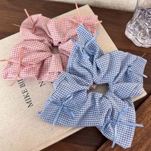 Close-up of pink and blue checkered scrunchies with delicate bows on a book