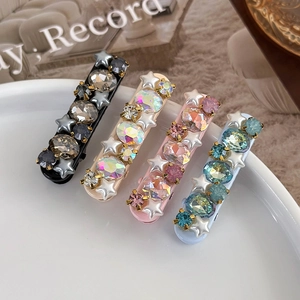 Detail of four colorful star pearl hair clips with crystals on a white ceramic plate