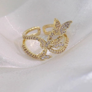 Vue macro détaillée d'une bague papillon dorée avec des zircons sur de la soie blanche
