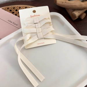 Detail of cream ballet bow hair clips made of ribbed ribbon on fashion display card