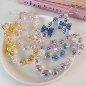 Detail of colorful aurora bead phone charms with resin bowknots on a white display plate