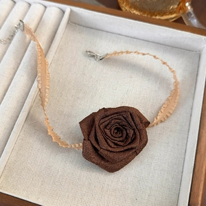 Detail of fabric rose choker with adjustable silver metal clasp on jewelry tray