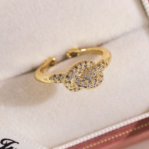 Détail d'une bague papillon dorée avec zircons incrustés sur écrin en velours crème