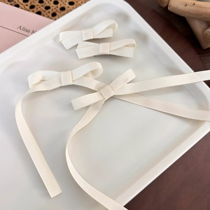 Detail of beige ribbed ribbon bow hair clips set in a decorative ceramic tray
