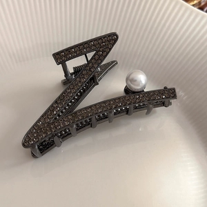 Vue détaillée d'une pince à cheveux en forme de Z avec strass gris et une perle blanche