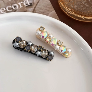 Detail of star-shaped rhinestone and pearl hair clips set on a ceramic tray