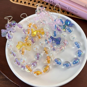 Close-up of colorful iridescent beaded phone straps with bow charms on a white plate