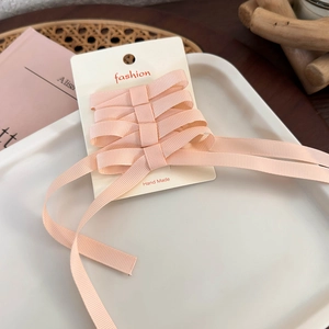 Detail of pink grosgrain ribbon bow hair clips with long streamers on a display card