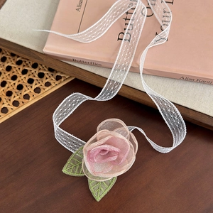 Détail de la rose en résille rose et feuilles brodées sur ruban de choker en dentelle