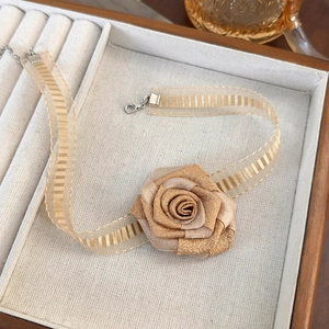 Close-up of champagne organza ribbon choker featuring a pearlescent fabric rose detail