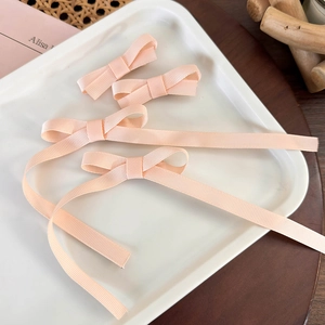 Detail of four pink ribbon bow hair clips with long streamers in a white tray